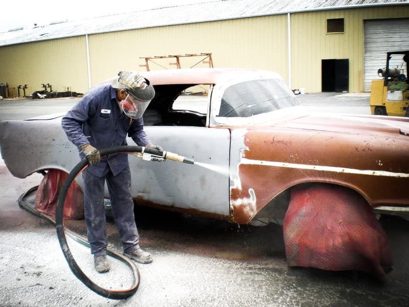 Technician blasting the body of a vintage vehicle