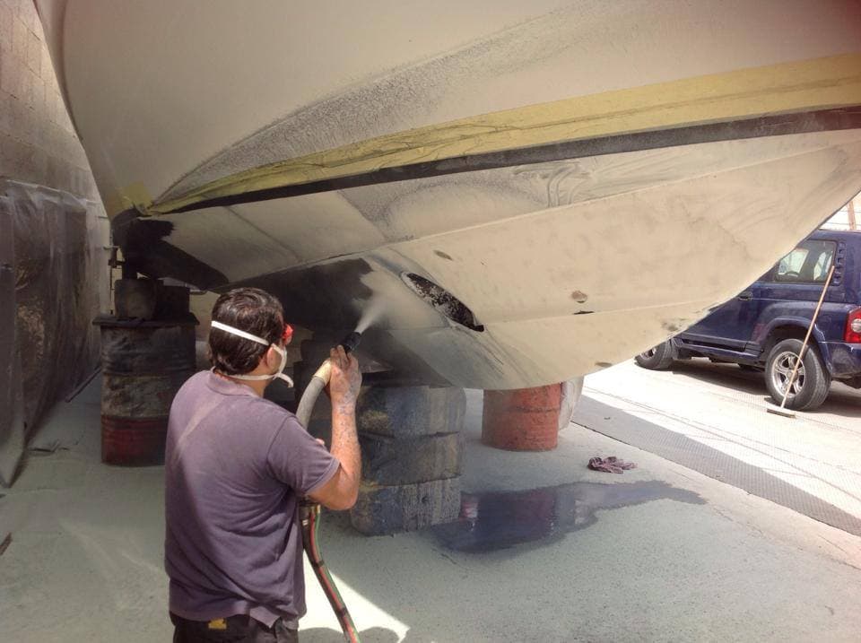Technician preparing the underside of a boat hull